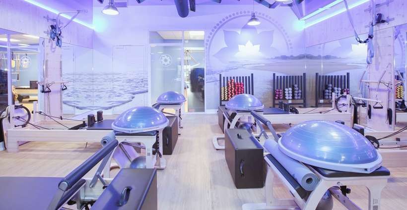 Instructrice accompagnant des adhérentes pendant un cours dans un studio Club Pilates
