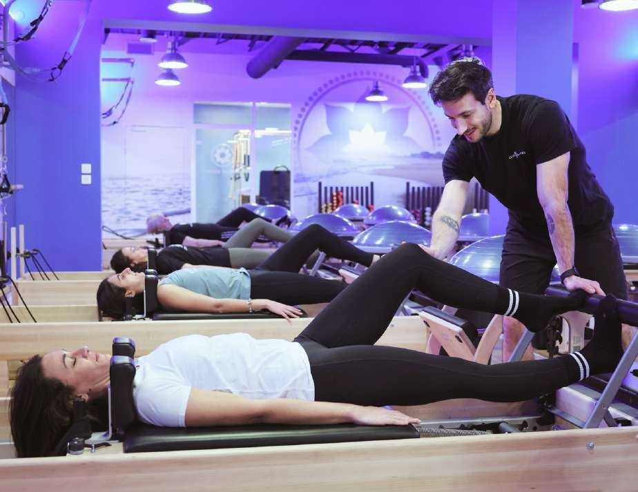 Coach et adhérentes sur des Reformers dans un studio Club Pilates